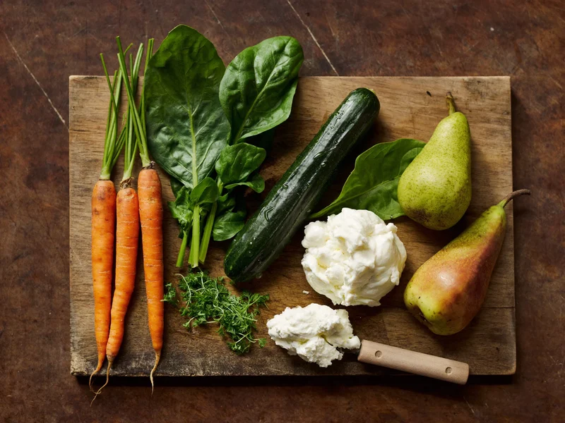Tagliere di legno con verdure di stagione, ricotta, pere ed erbe fresche